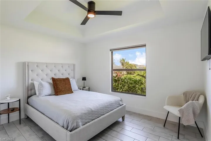 2nd guest Room featuring a tray ceiling with a ceiling fan, a window with exterior landscaping with blackout shades for late riser or plenty of sunshine.