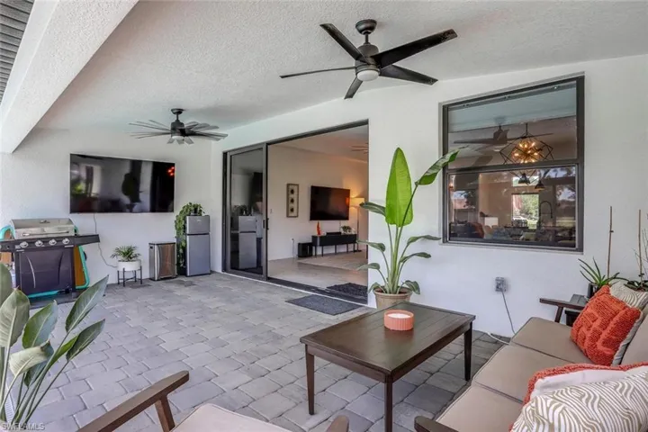 Spacious covered patio featuring paver flooring, dual ceiling fans, and a large impact glass sliding glass door