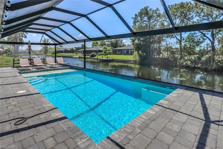 Screened-in pool deck featuring a saltwater heated pool with integrated steps, surrounded by sealed pavers.