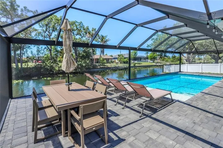 Screened-in outdoor living space with a large swimming pool and paver decking