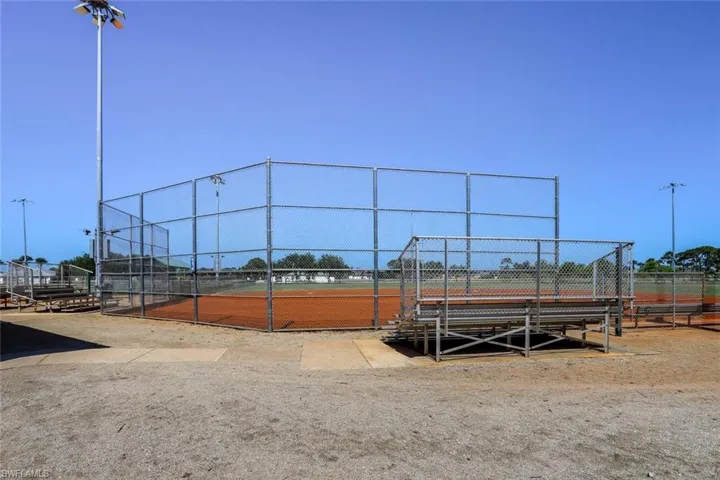 Softball field featuring a dirt infield, chain-link fencing, and spectator bleachers
