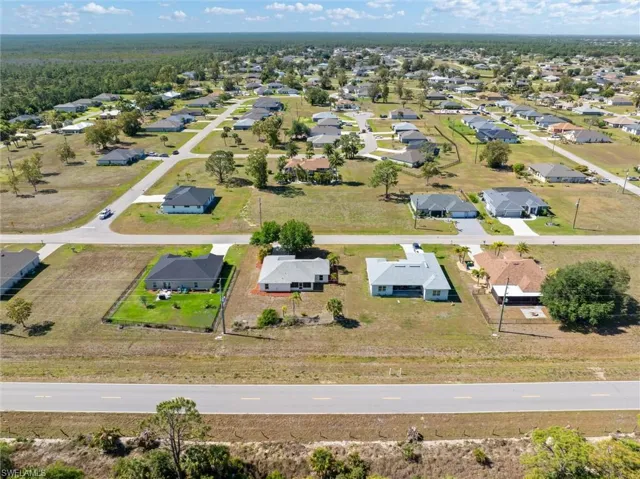 Aerial view showcasing a residential development featuring single-story homes with various roof styles and ample lot sizes
