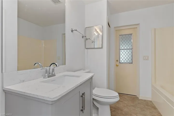Bathroom featuring a vanity with a white countertop and integrated sink, chrome faucet, and a large mirror