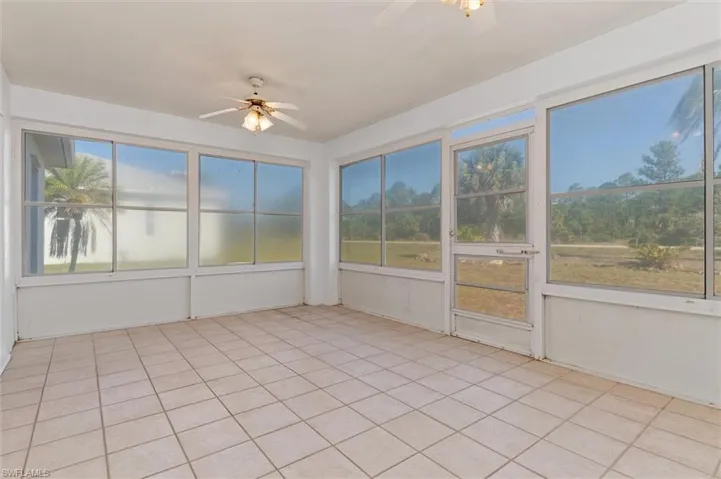 Enclosed sunroom featuring light-toned tile flooring, multiple ceiling fans with light kits, and expansive windows