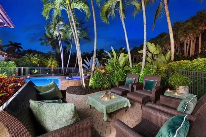 The secluded sitting area behind the home looks out over the pool, pond, fountain and heavily-landscaped privacy wall of lit palms.