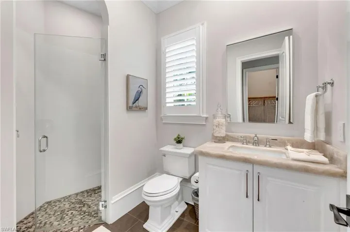Another exquisitely-redone bathroom, with gorgeous, Cristallo quartzite top, new bath fixtures, new shower and floor tiles, frameless shower door and new plantations shutters.