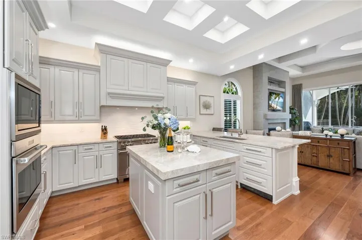 This remodeled kitchen underwent a facelift:  raised, coffered ceilings with ambient lights added, leathered Taj Mahal quartzite counters, Emtek polished nickel hardware, Kohler fixture, granite sink and subtle, new tile backsplash.  A dream kitchen!