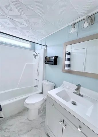 Bathroom featuring vanity, shower / bath combination with curtain, and light marble finish flooring