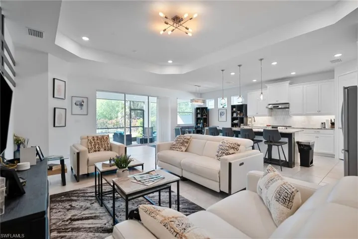 Living room featuring a tray ceiling, suspended lighting, and light tile patterned floors