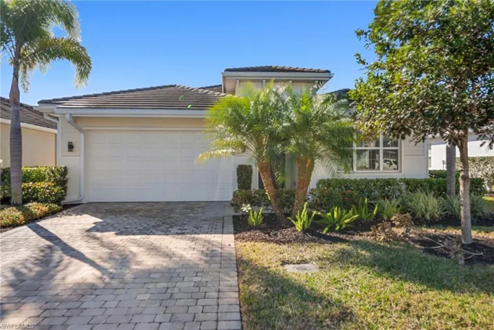 View of front of home with decorative driveway, a garage, a tiled roof, and stucco siding