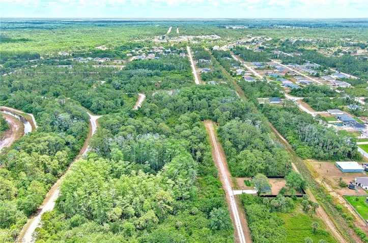 Aerial view of property and surrounding area featuring a forest