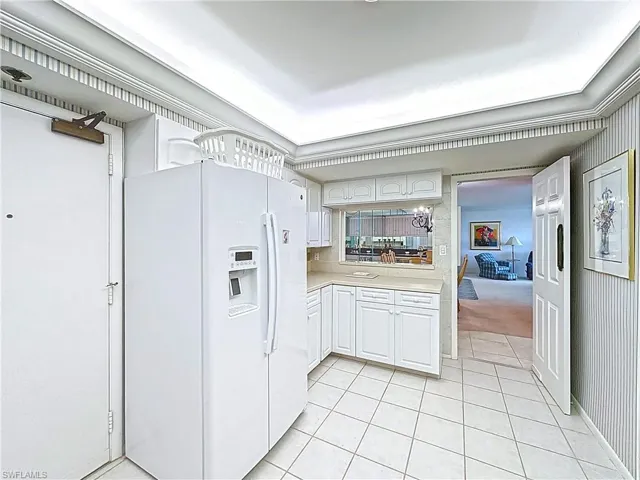 Kitchen featuring light carpet, white cabinetry, white refrigerator with ice dispenser, light countertops, and light tile patterned floors