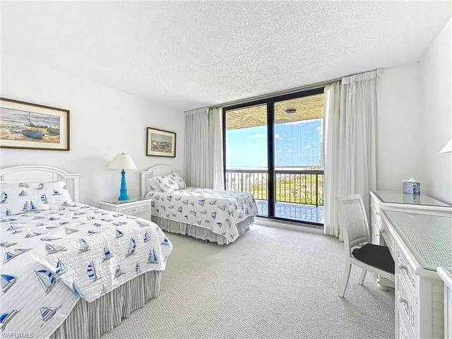 Carpeted bedroom featuring a wall of windows, a textured ceiling, and access to exterior
