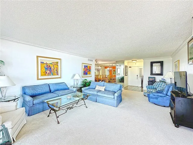 Living room featuring visible vents, carpet, a textured ceiling, and ornamental molding