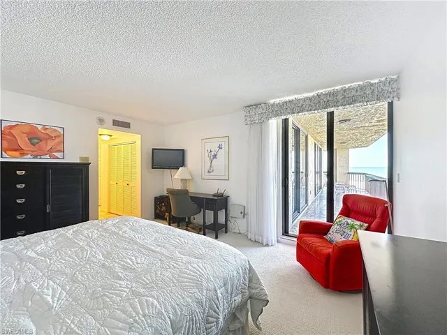 Bedroom featuring a textured ceiling, visible vents, carpet flooring, and access to outside