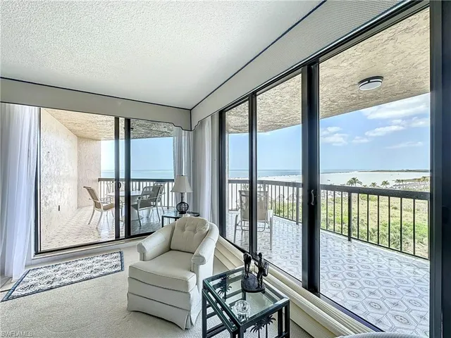 Sunroom / solarium featuring a textured ceiling, carpet floors, and a water view