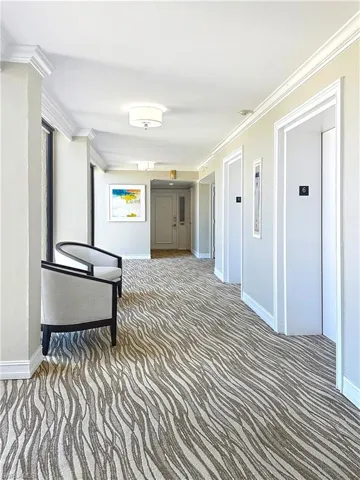 Corridor featuring elevator, carpet floors, baseboards, and ornamental molding