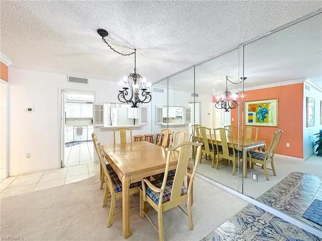 Dining space featuring visible vents, crown molding, and a notable chandelier