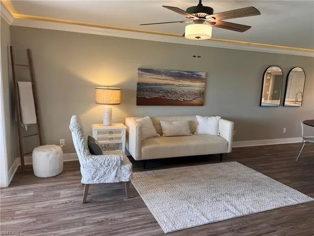 Living area with crown molding, luxury vinyl tile floors, and ceiling fan