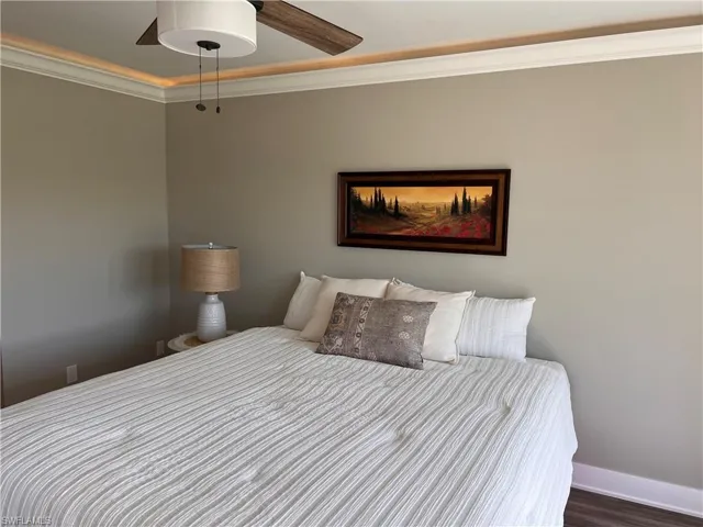 Primary bedroom with ornamental molding, a ceiling fan, and wood finished floors