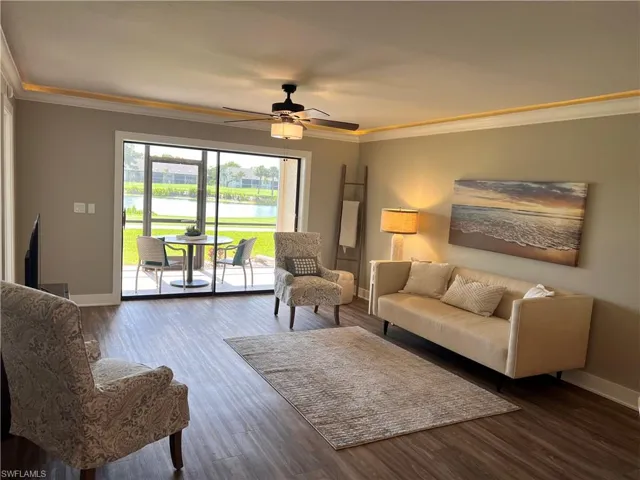 Living room featuring crown molding, a water view, luxury vinyl tile floors, and a ceiling fan
