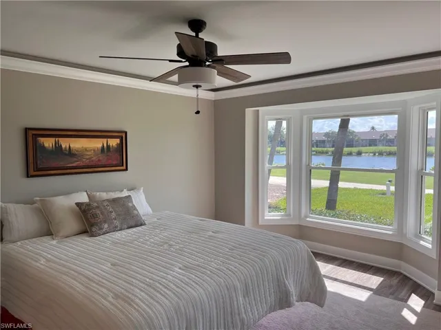 Primary Bedroom with ornamental molding, luxury vinyl tile floors, a water view, and a ceiling fan