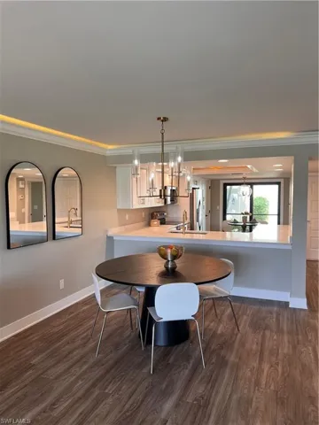 Dining room featuring ornamental molding, luxury vinyl tile floors, and a chandelier