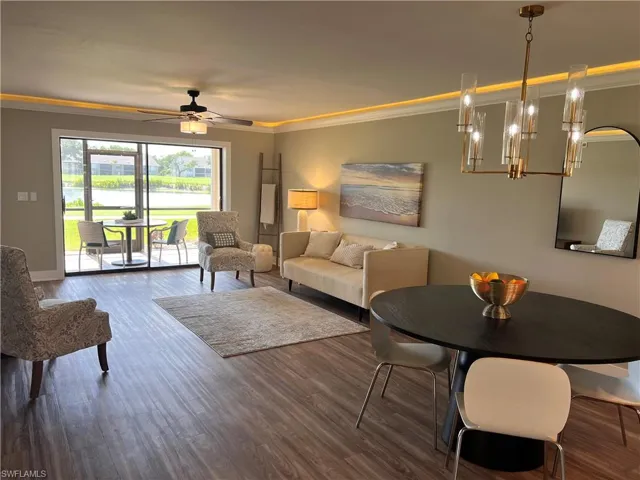 Living area featuring ornamental molding, a water view, luxury vinyl tile floors, a chandelier, and ceiling fan