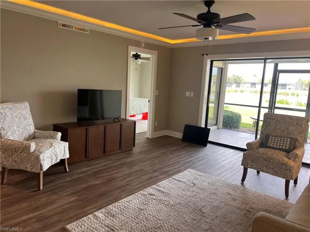 Living area with ornamental molding, luxury vinyl tile floors, and ceiling fan