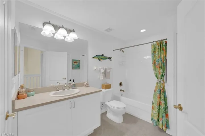 Full bath with shower / bath combo with shower curtain, vanity, and light tile patterned floors