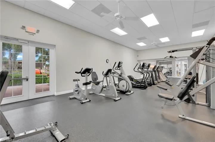Gym with ceiling fan, a paneled ceiling, and french doors