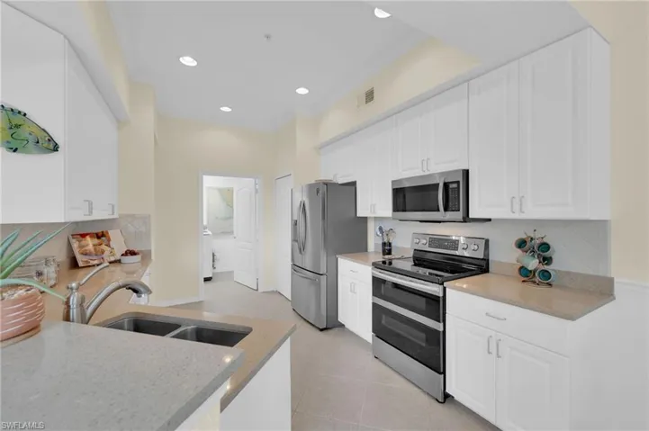 Kitchen featuring appliances with stainless steel finishes, backsplash, white cabinets, crown molding, and light tile patterned floors