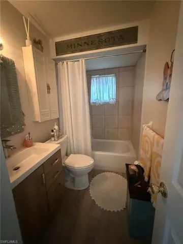 Full bath featuring shower / bathtub combination with curtain, vanity, toilet, and wood finished floors