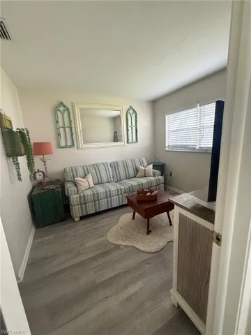 Living room featuring visible vents, baseboards, and wood finished floors