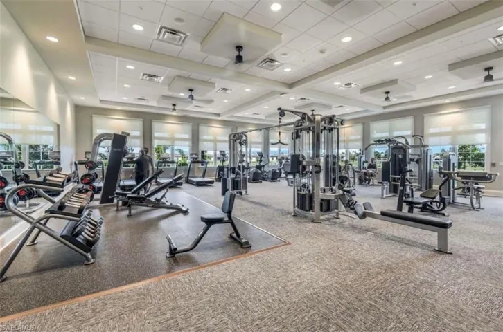 Exercise room featuring healthy amount of natural light, a tray ceiling, recessed lighting, and a drop ceiling