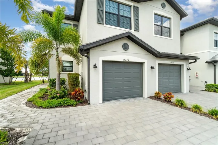 View of front of property with an attached garage, decorative driveway, and stucco siding