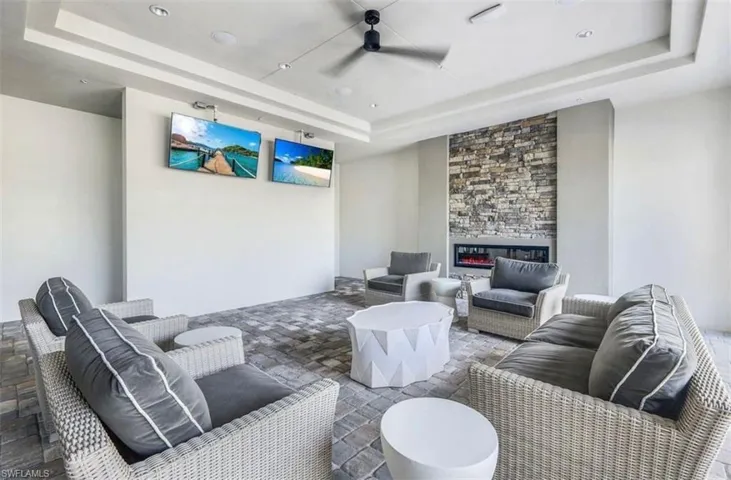 Living area with a raised ceiling, ceiling fan, and a fireplace