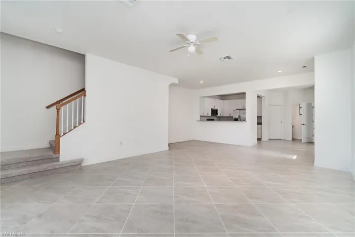 Unfurnished living room with stairs, a ceiling fan, light tile patterned floors, and recessed lighting