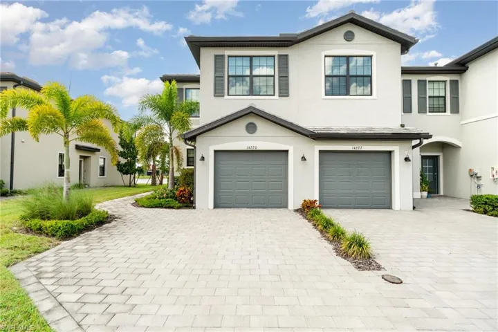 View of front facade with decorative driveway, a garage, and stucco siding