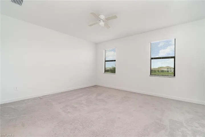 Unfurnished room with light colored carpet and ceiling fan
