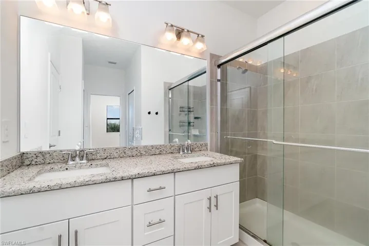 Full bath featuring double vanity and a shower stall