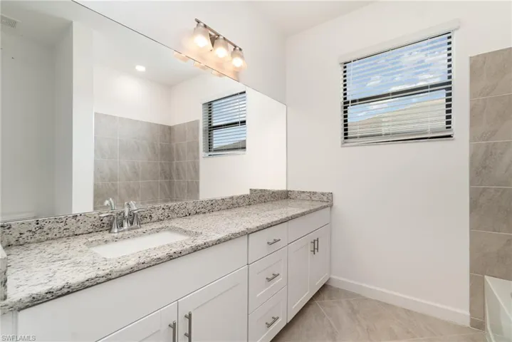 Full bath featuring vanity and light tile patterned flooring