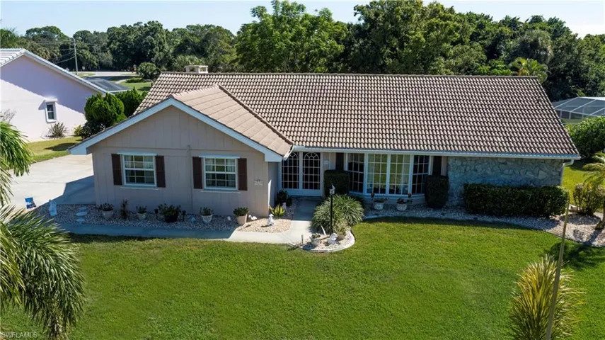 View of front of house featuring a tiled roof, a front lawn, and stone siding