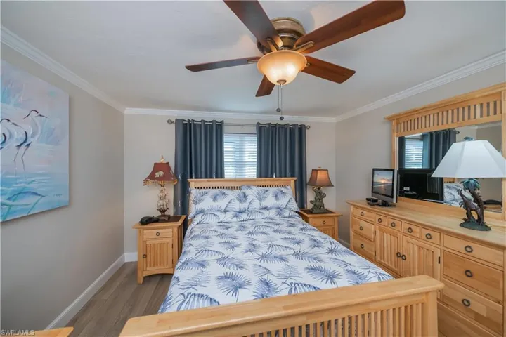 Bedroom with ornamental molding, light wood-style flooring, and ceiling fan
