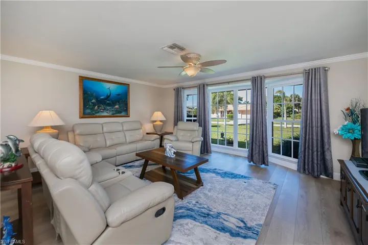 Living area with crown molding, LVP flooring, and ceiling fan