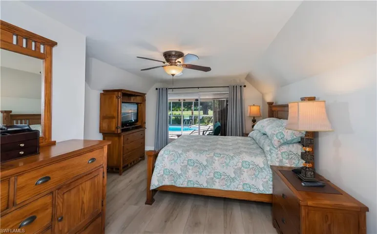 Bedroom featuring access to outside, a ceiling fan, light wood-type flooring, and vaulted ceiling
