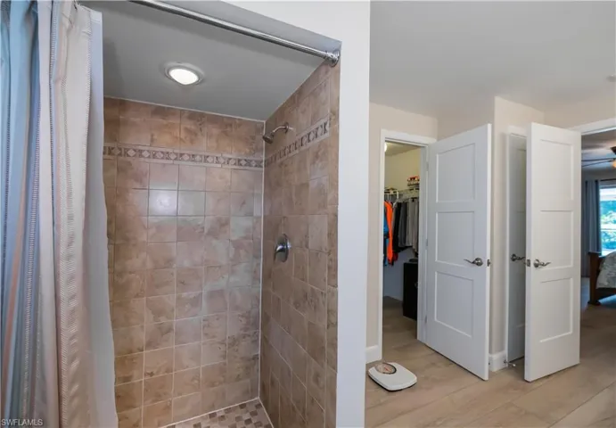 Bathroom featuring a spacious closet, a stall shower, and light wood-type flooring