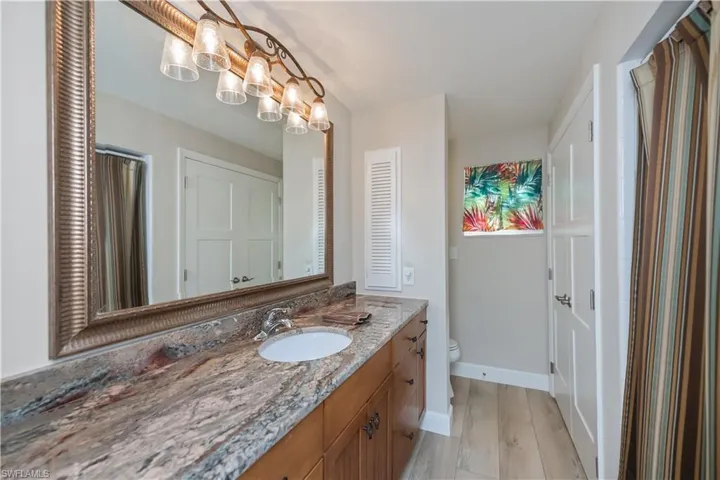 Full bath remodeled with quartz vanity, newer wood vanity and light vinyl plank  flooring