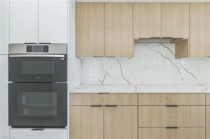 Kitchen featuring light stone counters, modern cabinets, a chandelier, recessed lighting, and hanging light fixtures