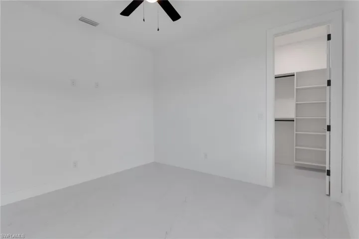 Empty room with dark tile patterned flooring and ceiling fan